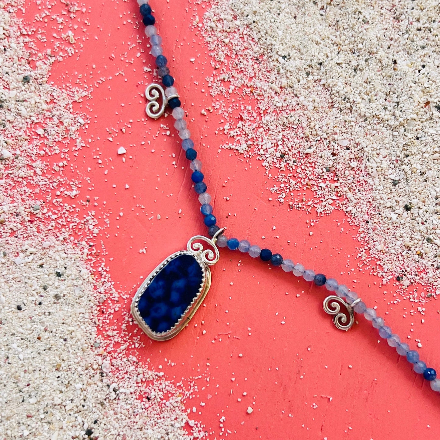 Necklace with blue pendant on a textured surface