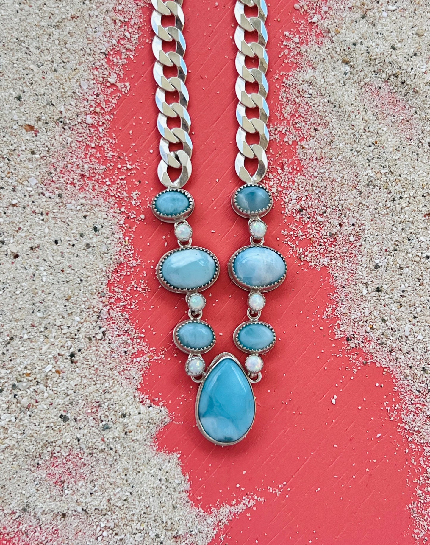 Necklace with blue teardrop pendants and silver chain on a textured surface