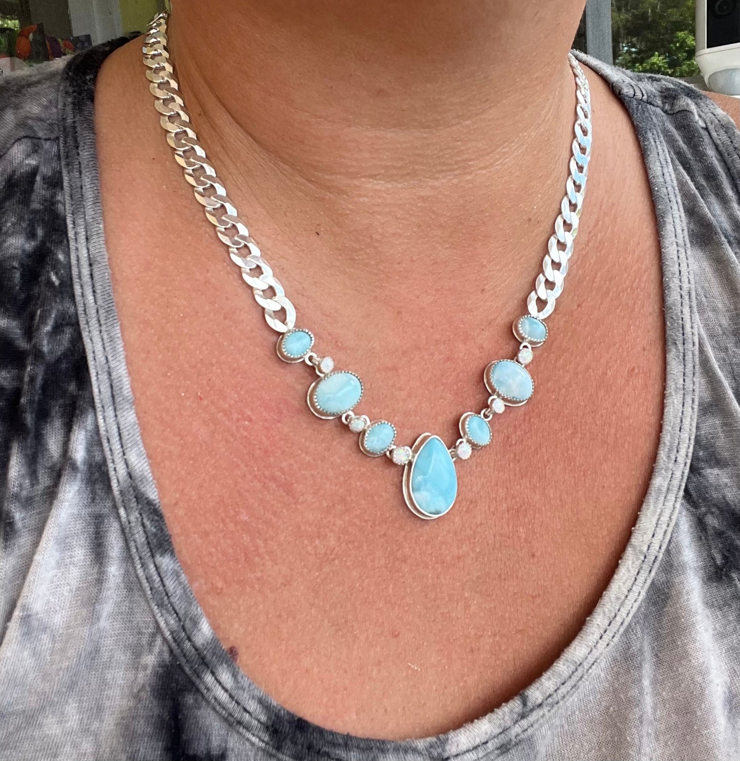 Necklace with blue stones and silver chain worn by a person