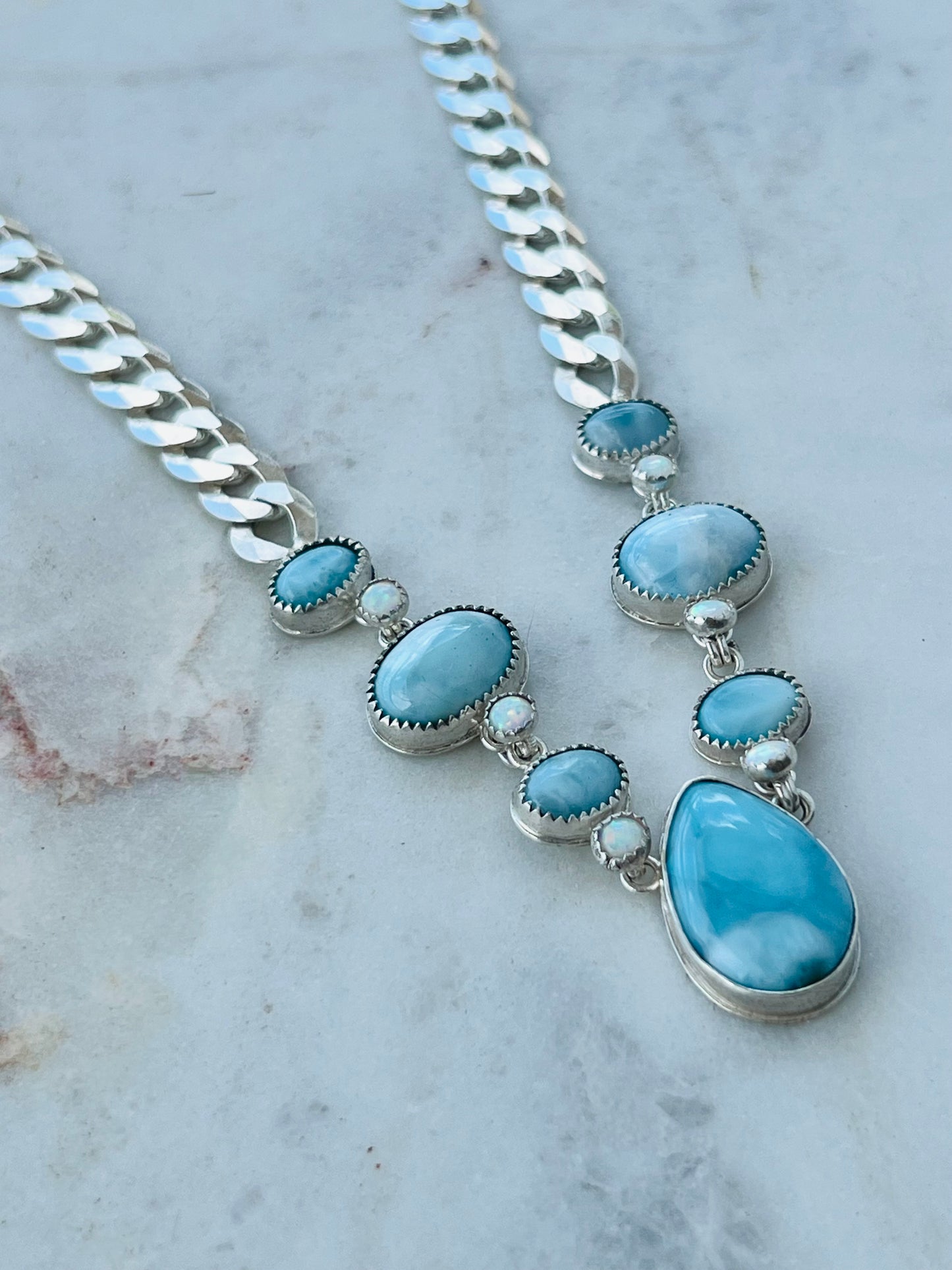 Necklace with blue stones and silver chain on a marble surface