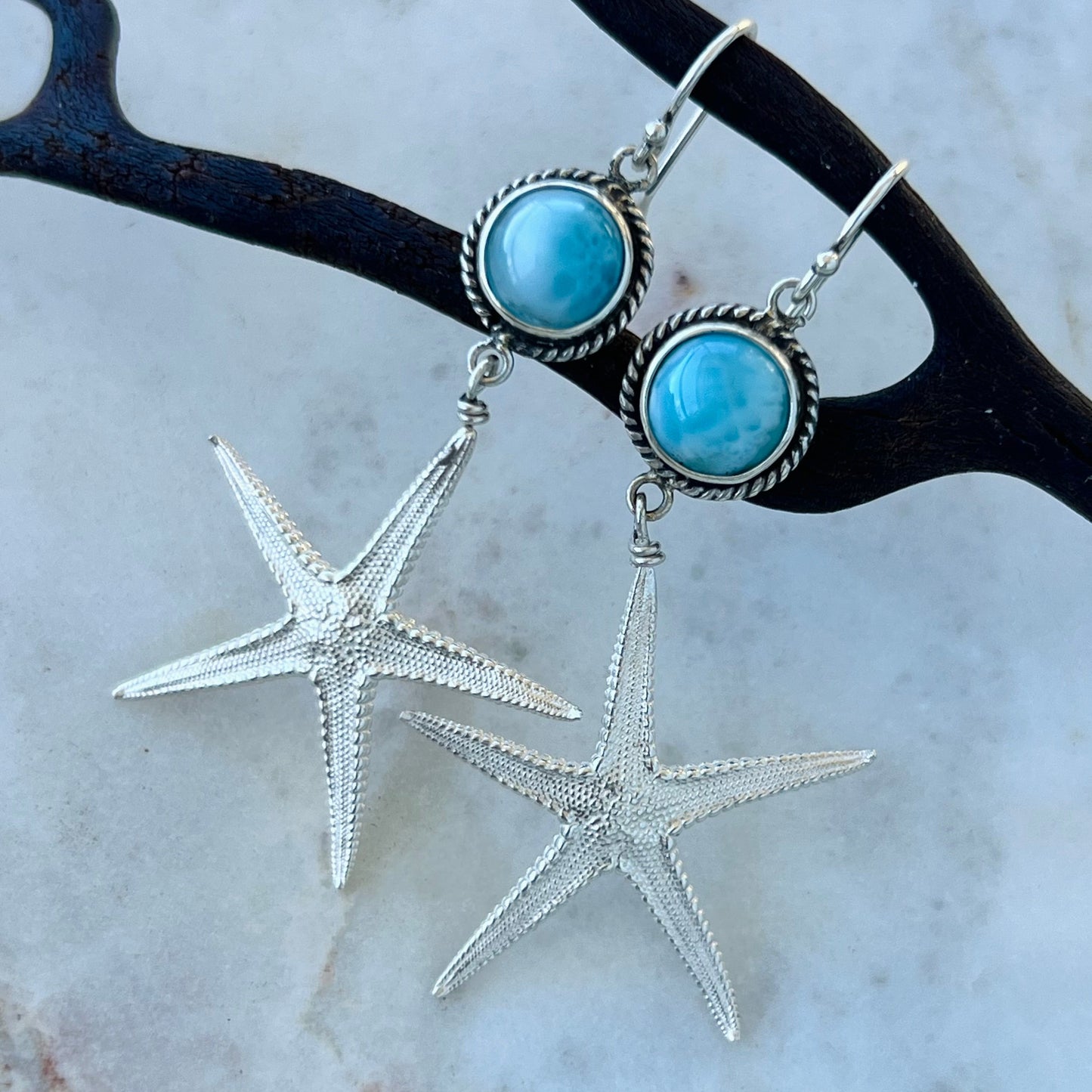 Silver starfish earrings with turquoise stones on a white background