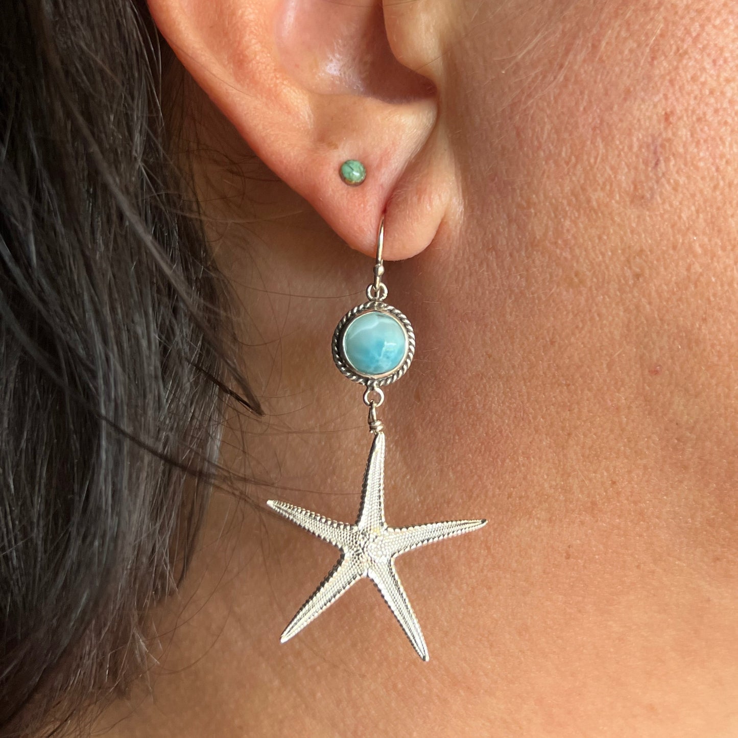 Starfish-shaped earring worn on an ear with a close-up view.