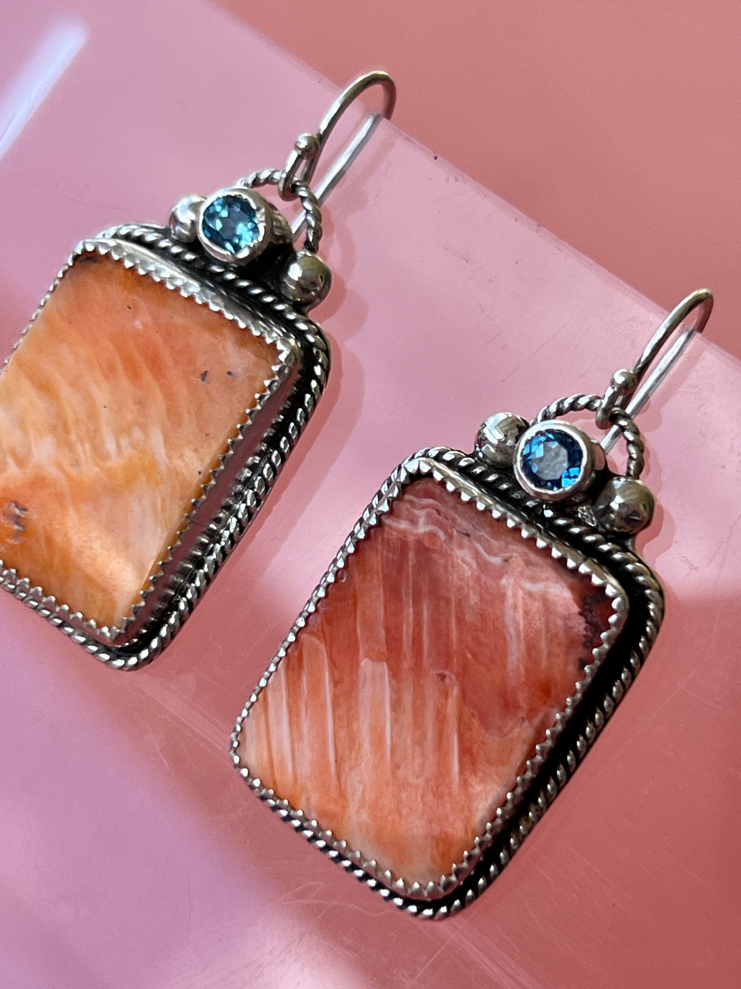 Pair of earrings with stone and gemstone details on a pink background