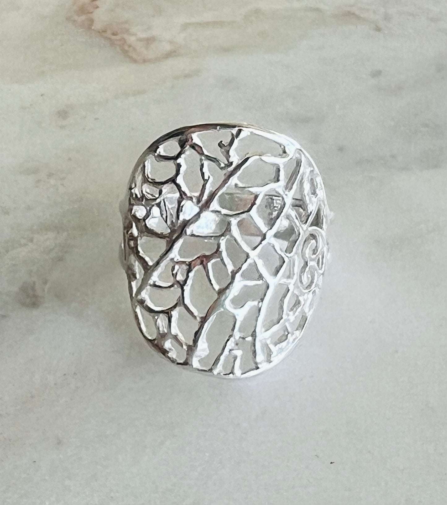 Silver ring with intricate design on a light gray background