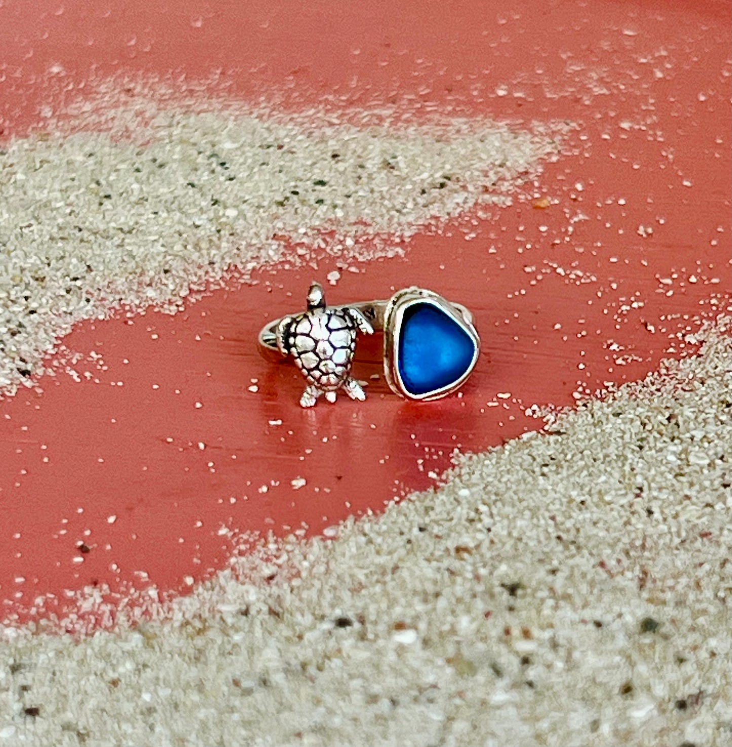 Two rings on a sandy surface with a red background