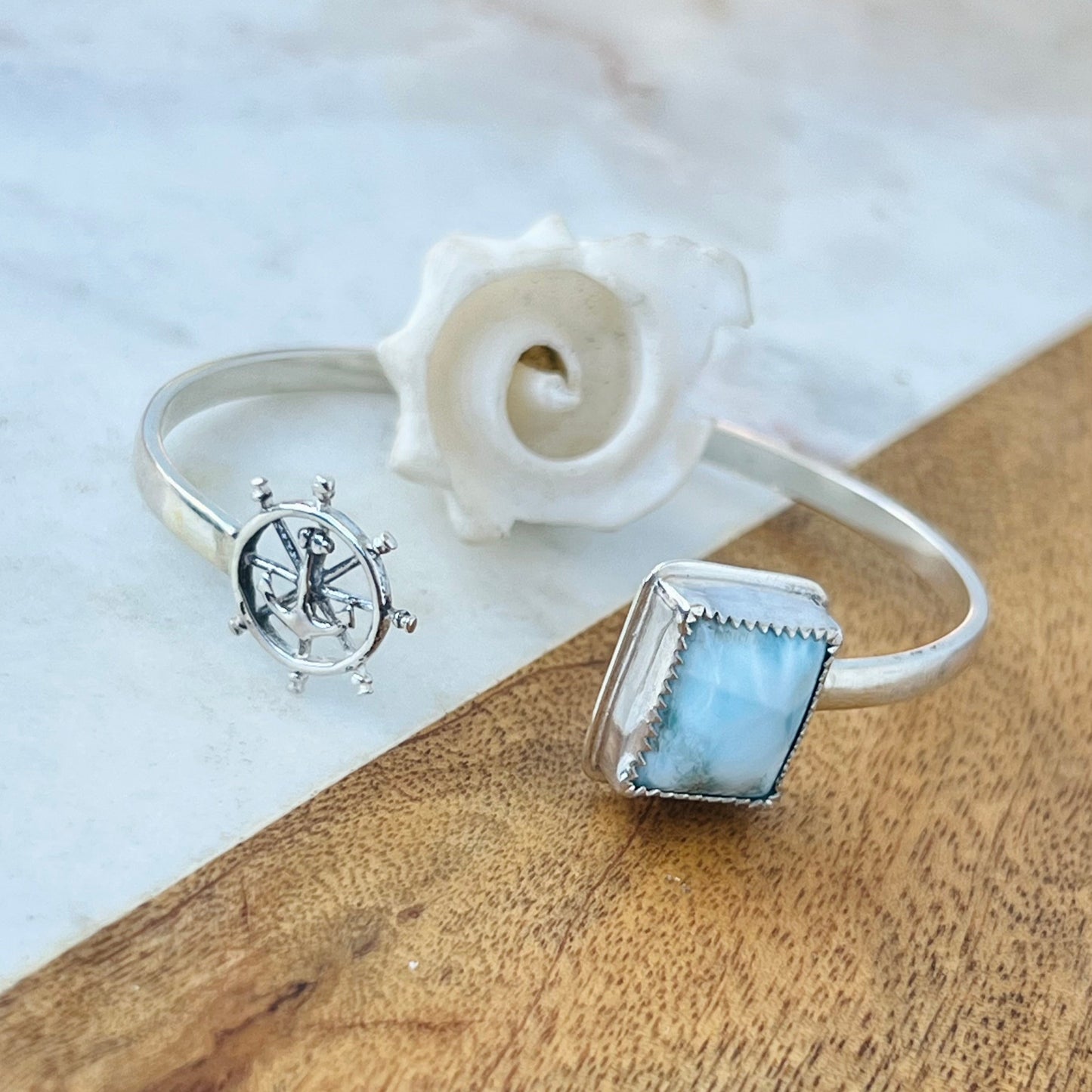 Two silver rings with gemstones on a wooden surface