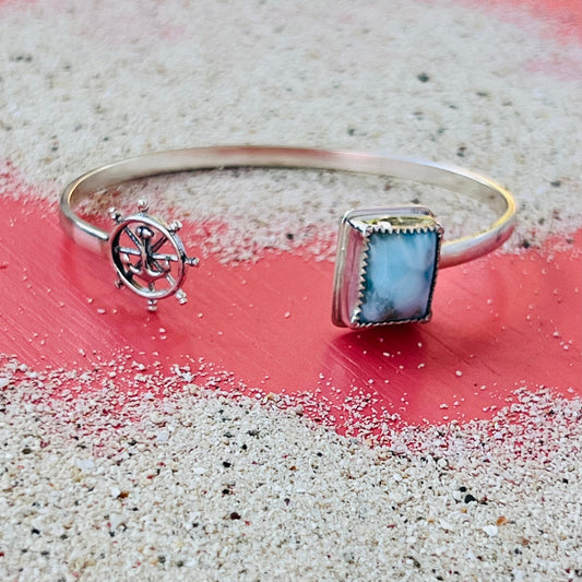 Silver bracelet with a square gemstone on a sandy surface