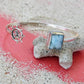 Silver bracelet with blue stone and ship wheel charm on a textured surface