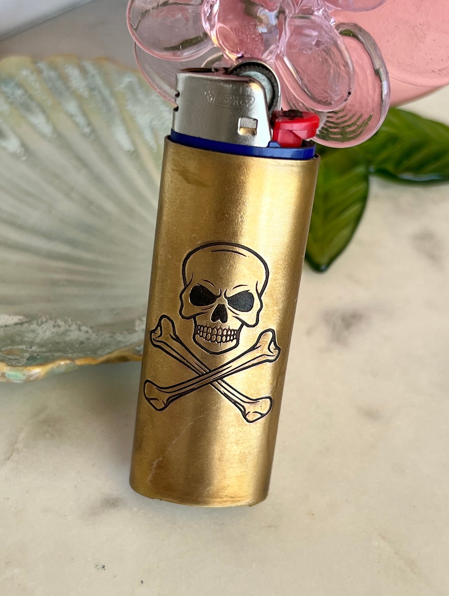 Brass lighter with skull and crossbones design on a light-colored surface.