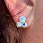 Close-up of an earring with three gemstones worn on an ear.