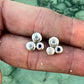Silver earrings with gemstones held between fingers against a natural background
