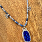 Necklace with blue pendant and beaded chain on a wooden surface