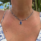 Necklace with a blue pendant worn by a person against a natural background