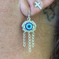 Close-up of an ear with a small gold earring featuring an eye design.