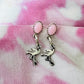 Flamingo-shaped charms with pink beads on a pink and white patterned fabric background