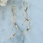 Gold spiral earrings on a light blue marble surface