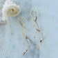 Gold earrings on a marble surface with a shell