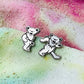 Two dancing bear earrings on a tie-dye fabric background