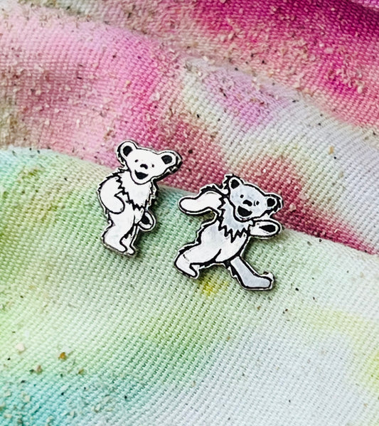 Two dancing bear earrings on a tie-dye fabric background