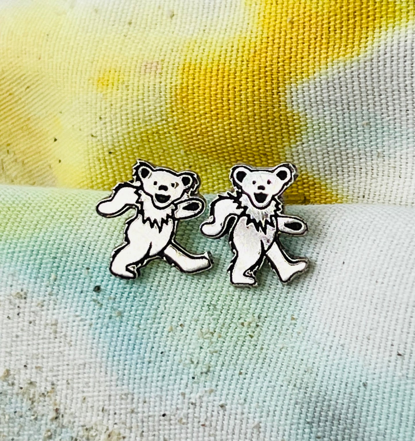 Pair of dancing bear earrings on a textured fabric background