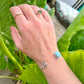 Hand with multiple rings on a green leafy background