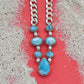 Necklace with blue teardrop pendants and silver chain on a textured surface