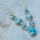 Necklace with blue stones and silver chain on a marble surface