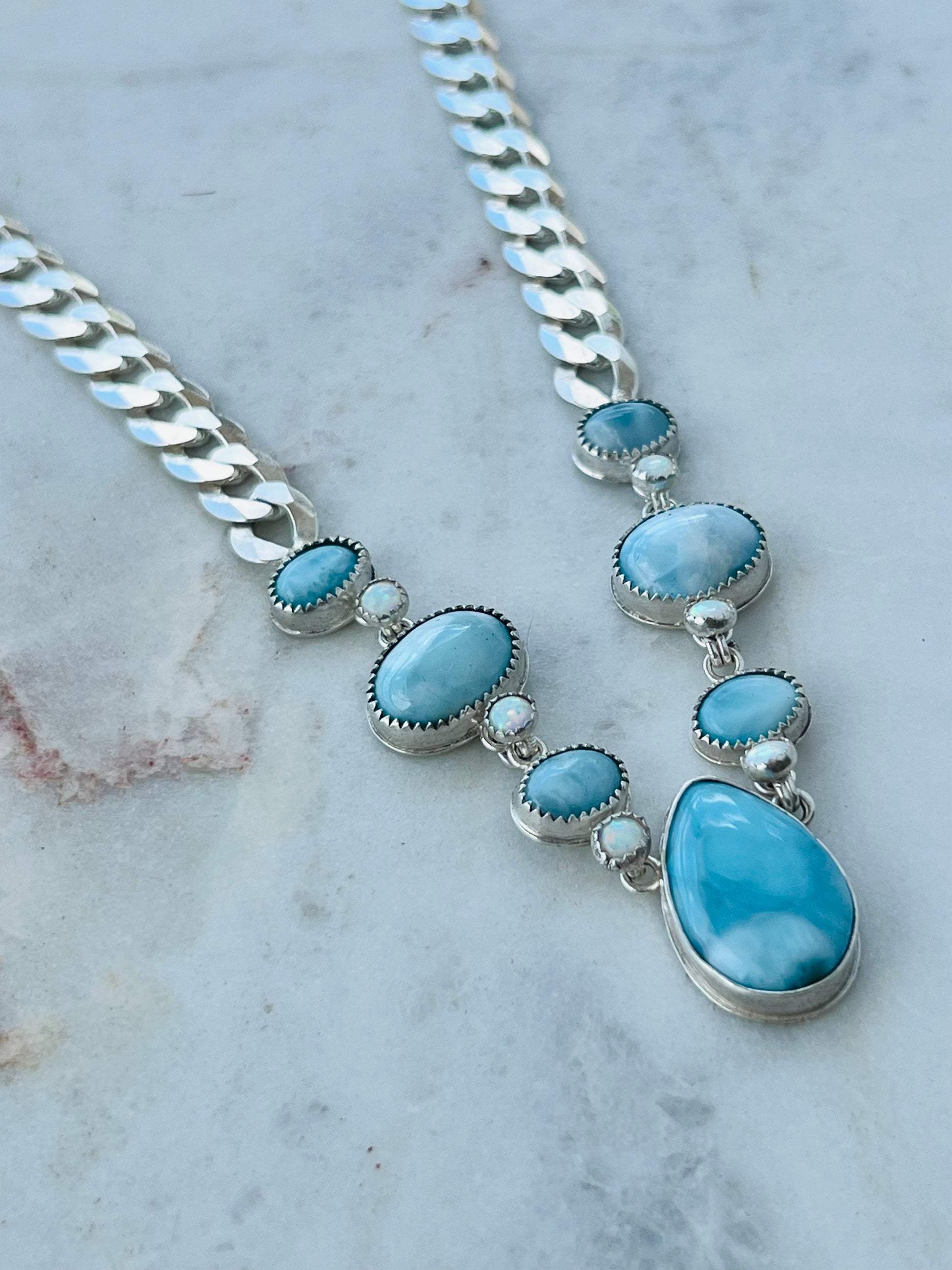 Necklace with blue stones and silver chain on a marble surface