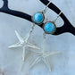 Silver starfish earrings with turquoise stones on a white background