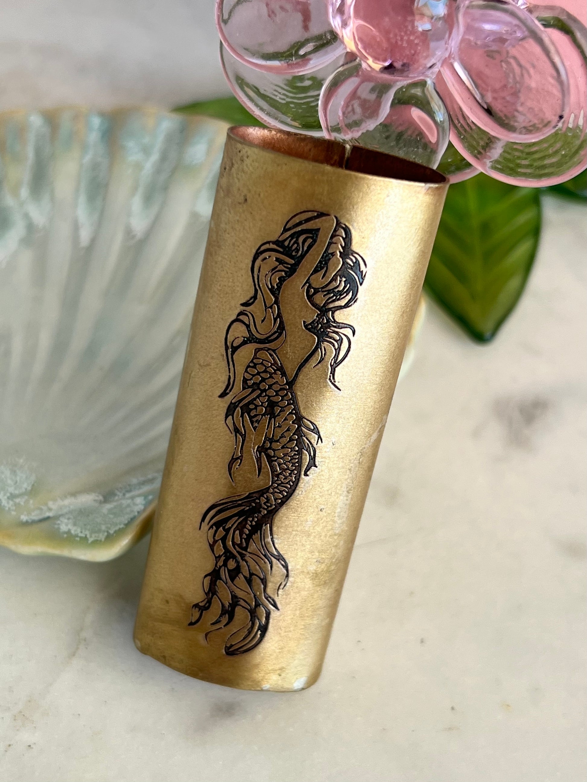 Brass vase with mermaid design on a marble surface
