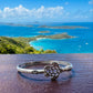 Silver turtle bracelet on a wooden surface with a scenic ocean view in the background