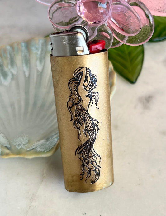 Bronze lighter with mermaid design on a light background