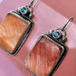 Pair of earrings with stone and gemstone details on a pink background