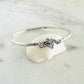 Silver bracelet with shell design on a white shell against a marble background