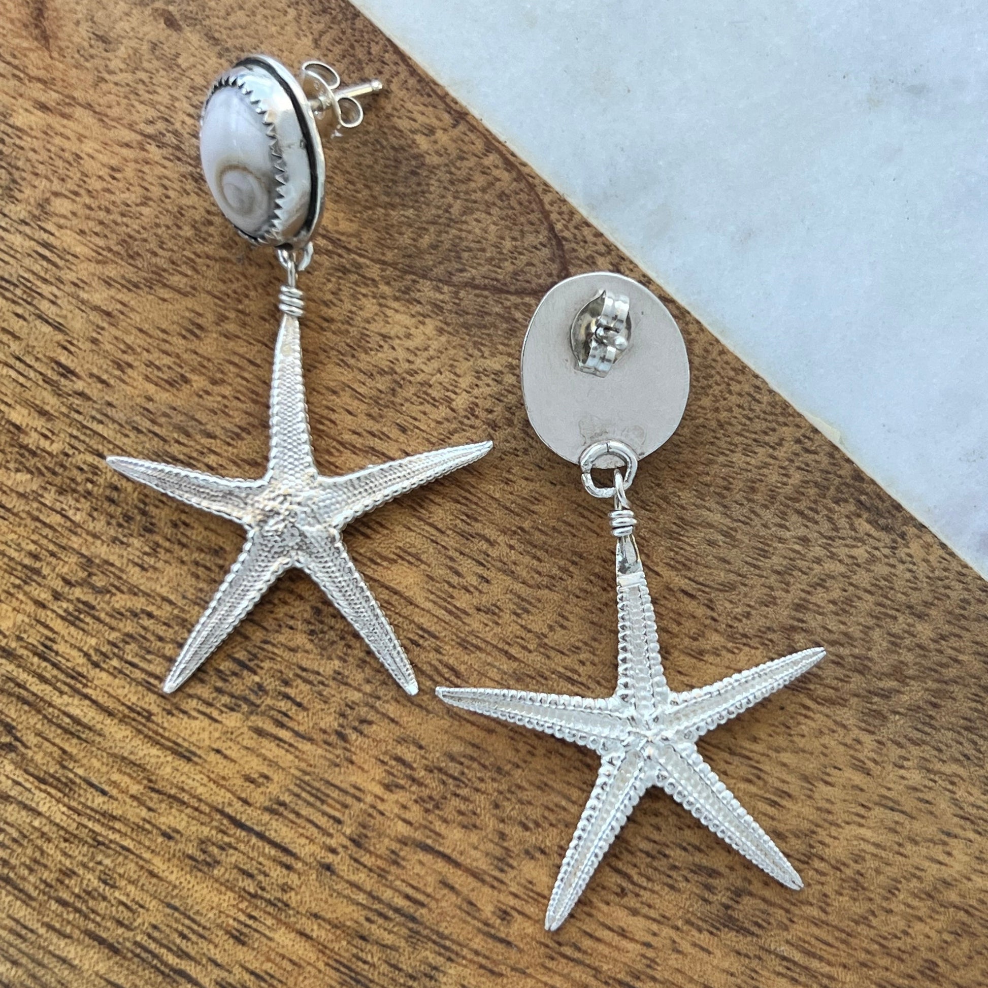 Silver starfish-shaped earrings on a wooden surface