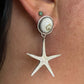 Silver starfish earring worn on a person's ear