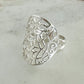 Silver ring with intricate design on a light gray background