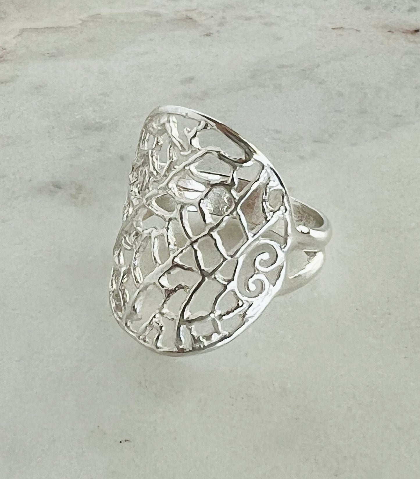 Silver ring with intricate design on a light gray background