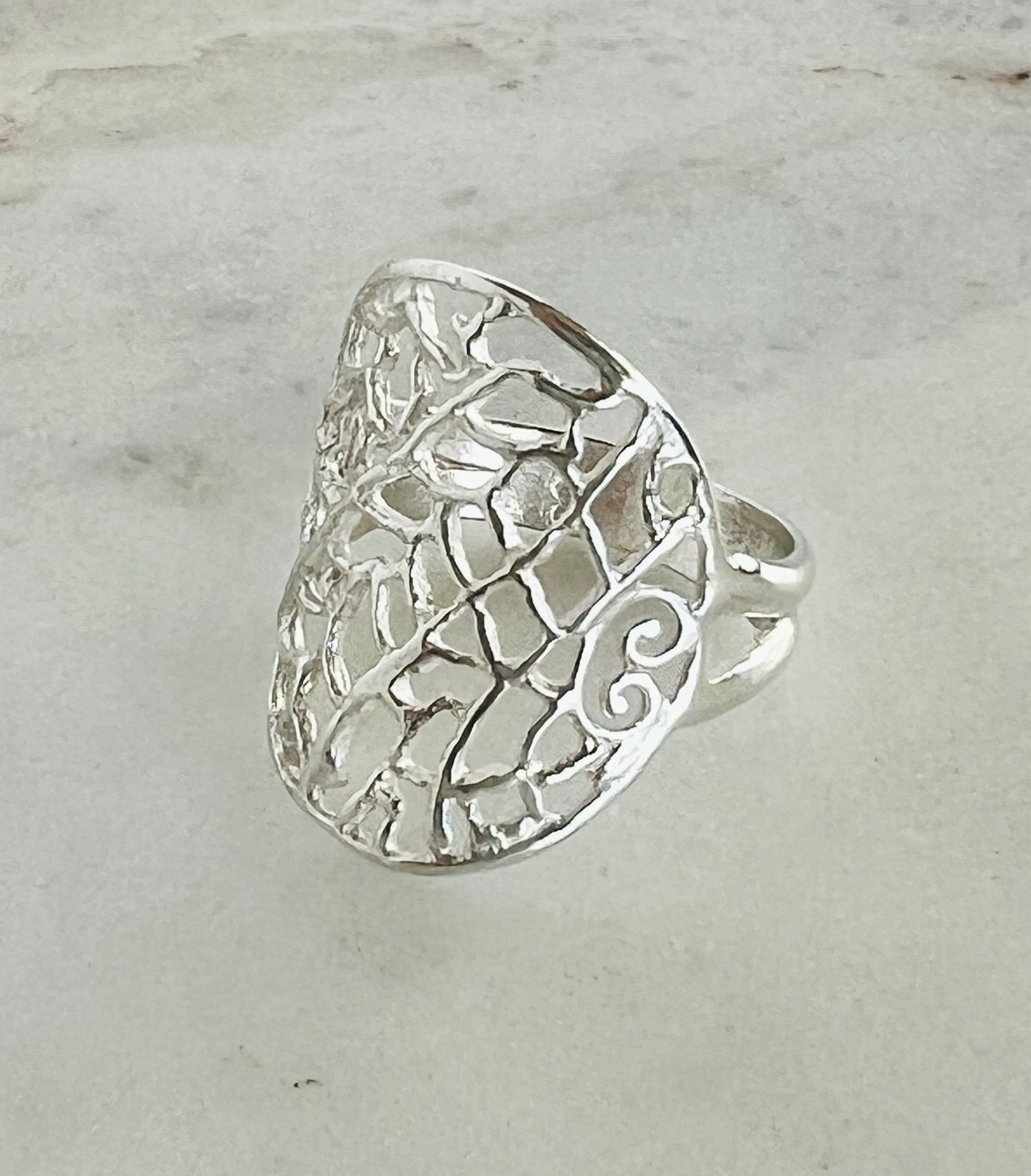 Silver ring with intricate design on a light gray background