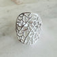 Silver ring with intricate design on a light gray background