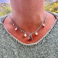 Necklace with a pendant worn by a person against a scenic background