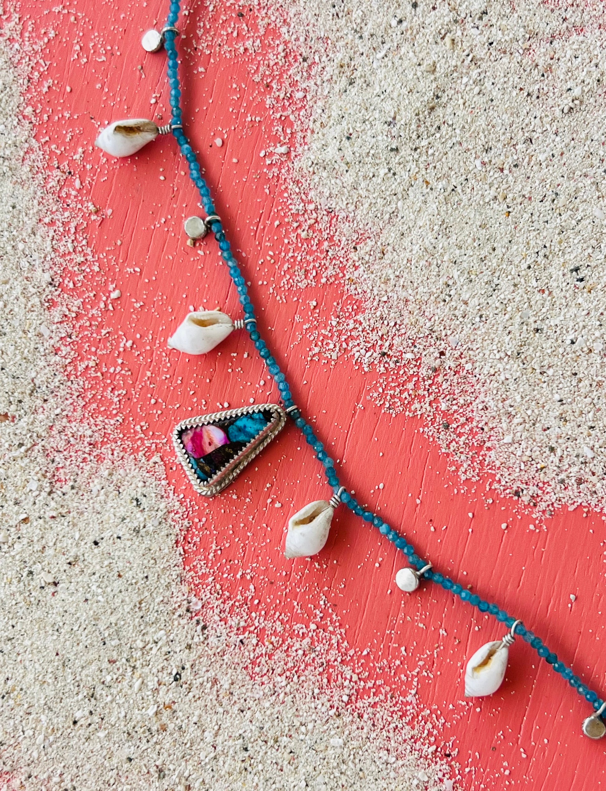 Necklace with shell pendants on a sandy surface