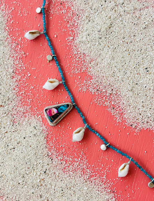 Necklace with shell pendants on a sandy surface