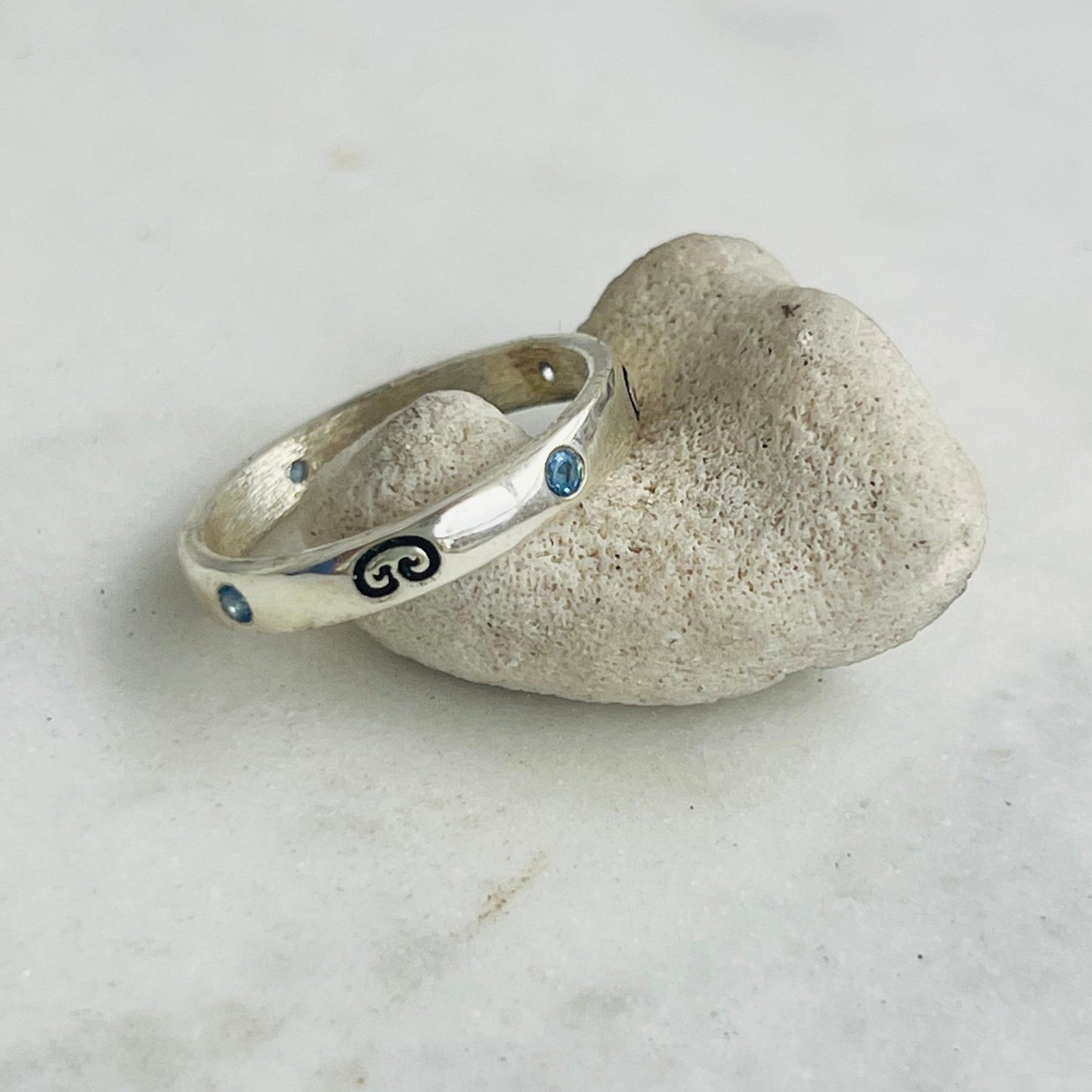 Silver ring with blue stones on a stone surface