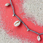 Necklace with shell pendants on a pink and white sandy background