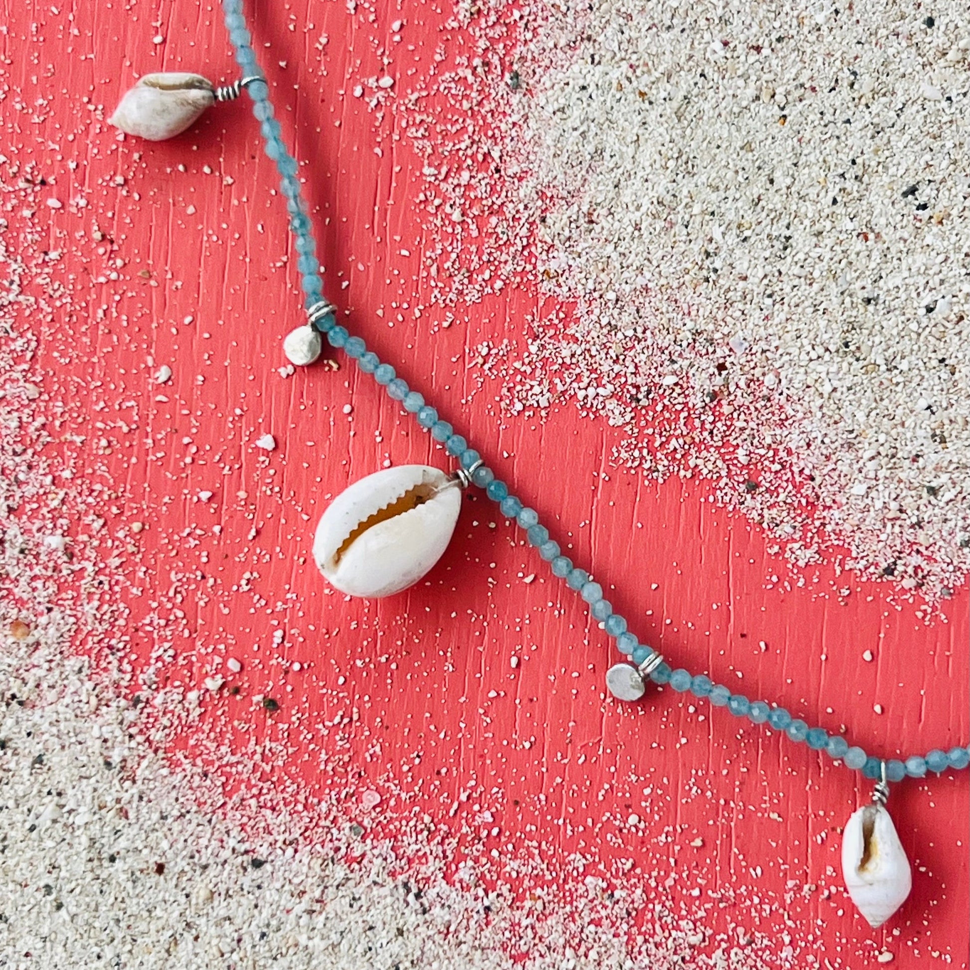 Necklace with shell pendants on a pink and white sandy background