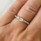 A close-up of a hand wearing a silver eternity ring with a central emerald-cut sapphire and smaller side sapphires.