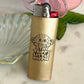 Gold lighter with a hippie design and text on a light-colored surface.