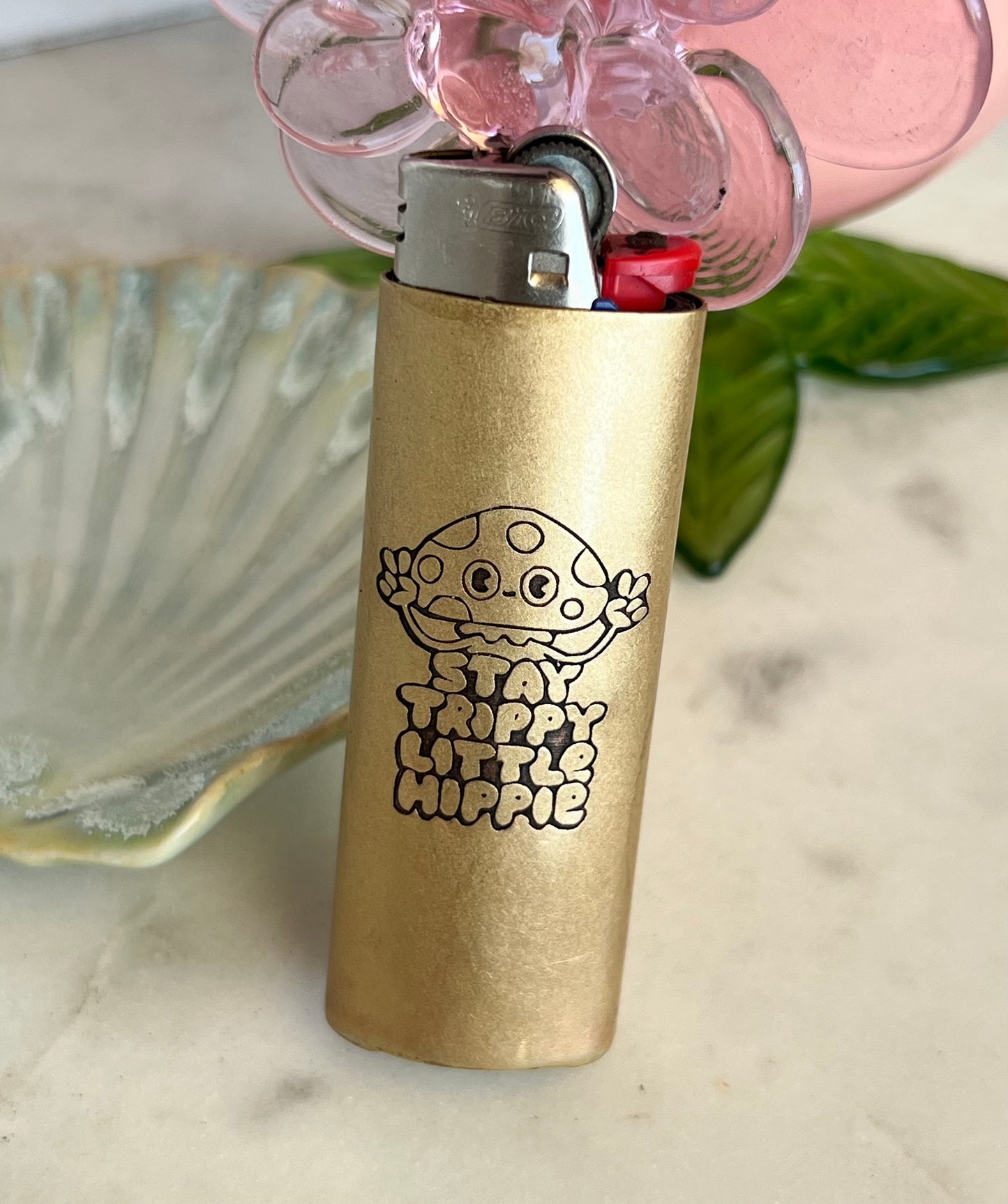 Gold lighter with a hippie design and text on a light-colored surface.
