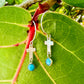 Silver earrings with turquoise stones on a green leaf